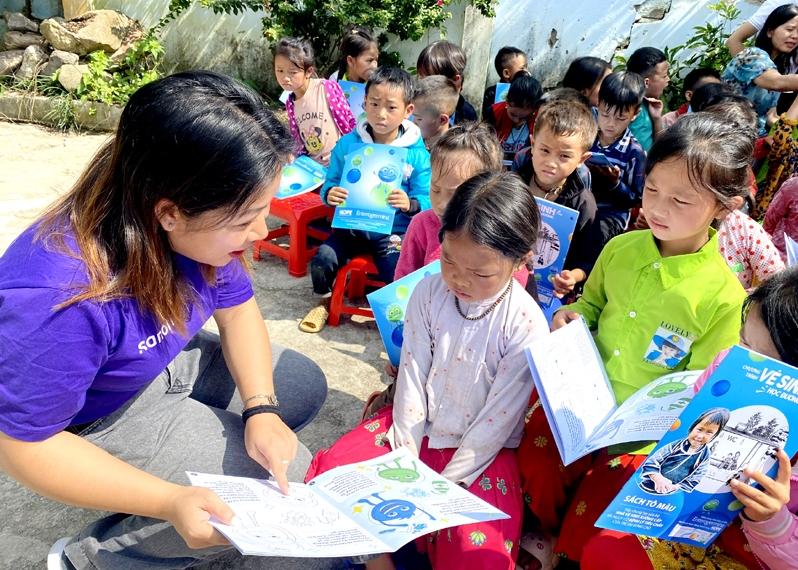 Tình nguyện viên Quỹ Hy vọng hướng dẫn học sinh Trường PTDTBT Tiểu học Ma Lé, xã Má Lé (Đồng Văn) tô màu sách về vệ sinh học đường.